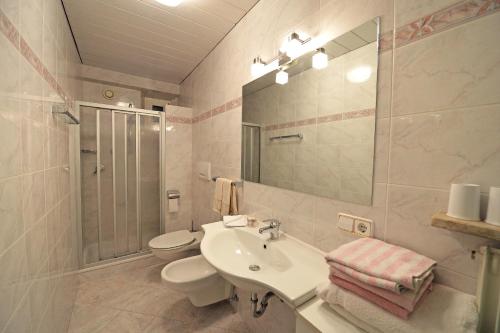 ein Badezimmer mit einem Waschbecken, einem WC und einem Spiegel in der Unterkunft Apartments Dolomie in St. Ulrich in Gröden