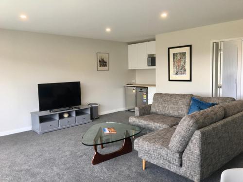 a living room with a couch and a tv at Minaret Ridge Retreat in Wanaka