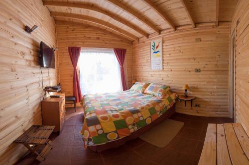 ein Schlafzimmer in einem Blockhaus mit einem Bett und einem Fenster in der Unterkunft Eco Cabañas Algarrobo in Algarrobo