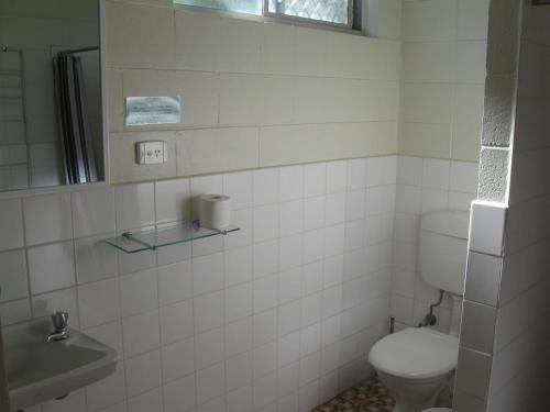 a white bathroom with a toilet and a sink at Sunburst Motel in Gold Coast
