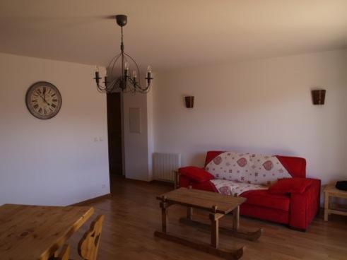 a living room with a red couch and a clock at La Pradella in Bolquere Pyrenees 2000