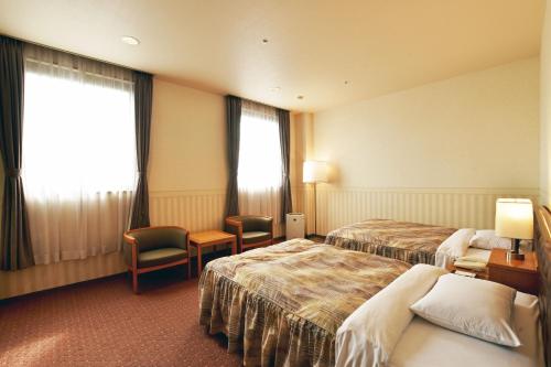 a hotel room with two beds and a window at Hotel Sapporo Sun Plaza in Sapporo