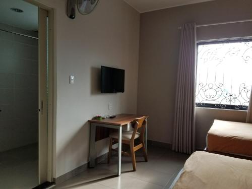 a bedroom with a desk and a television on the wall at Lee Hotel in Ho Chi Minh City