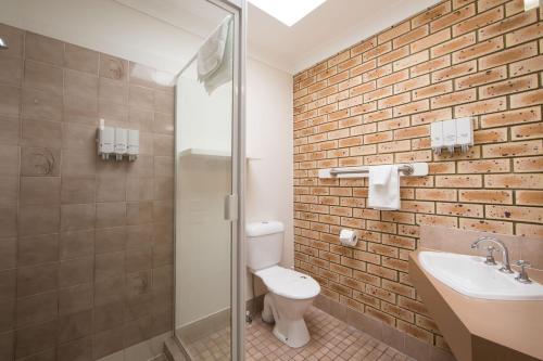 a bathroom with a white toilet and a sink at Caboolture Motel in Caboolture