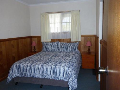 a bedroom with a bed with a window and two lamps at Platypus Park Country Retreat in Bridport