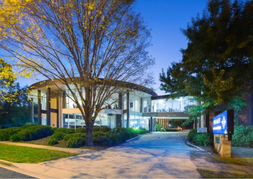 un grand bâtiment avec un arbre en face dans l'établissement Ramada Encore Belconnen, à Canberra
