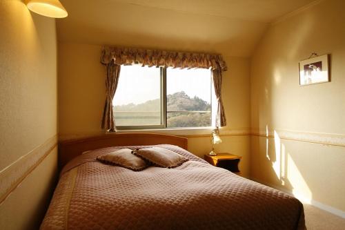 a small bedroom with a bed with a window at Koibito Misaki Pension Marine Mates in Izu