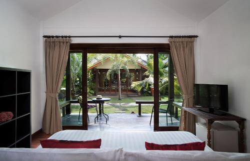1 Schlafzimmer mit 2 Betten, einem TV und einer Terrasse in der Unterkunft Mali Resort Pattaya Beach Koh Lipe in Ko Lipe