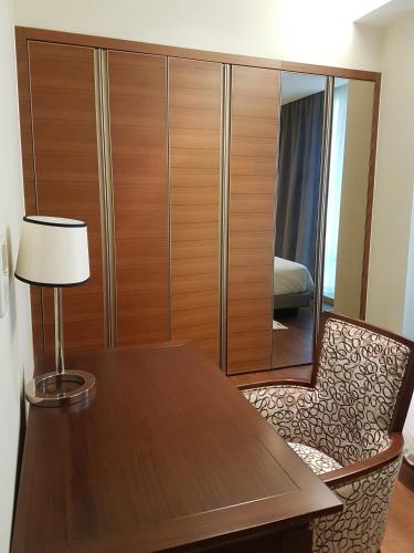 a wooden cabinet with a table and a lamp at Lotte The Residence in Hanoi