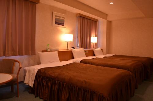 um quarto de hotel com duas camas e uma janela em Southern Cross Inn Matsumoto em Matsumoto