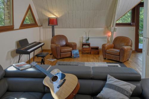a living room with a couch and a guitar at la maison dans les bois in Soucelles