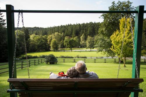 a man and a woman sitting on a swing at Hotel Kleins Wiese in Schmallenberg