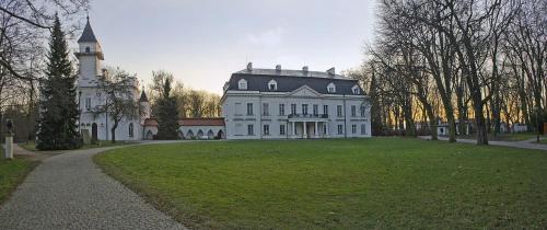 a large white house with a tower on a grass field at Dom Gościnny 8 km od Suntago, Deepspot in Radziejowice