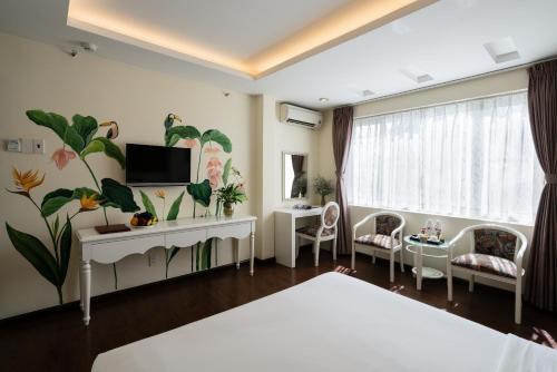 1 dormitorio con 1 cama y TV en la pared en Asian Ruby Center Point Hotel & Spa en Ho Chi Minh