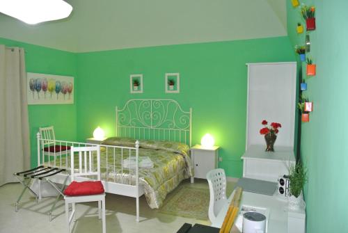 1 dormitorio con paredes verdes, 1 cama y sillas en Mamma Puglia Suite & Breakfast en Santeramo in Colle