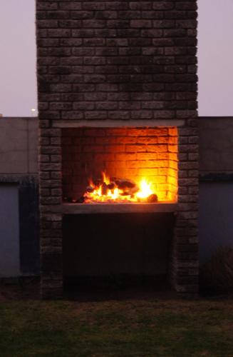 a brick fireplace with a fire in it at Sandy Shores 3 Henties in Hentiesbaai