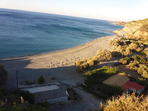a beach with a group of chairs and the ocean at Akrotiri Panorama- luxury rental apartments with sea view in Rodakino