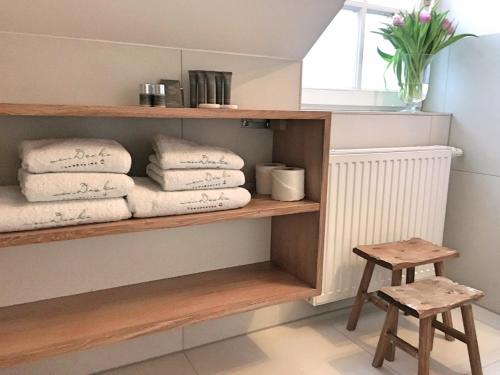 a shelf with towels and a stool in a bathroom at von Deska Townhouses - Ivy House in Hamburg