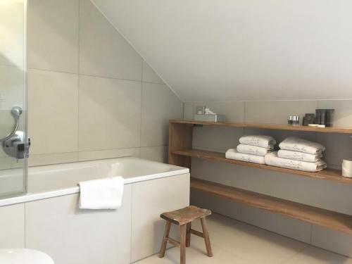 a bathroom with a tub and a stool and towels at von Deska Townhouses - Ivy House in Hamburg