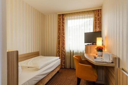 レールテにあるHotel Alte Postのベッドとデスクが備わるホテルルームです。