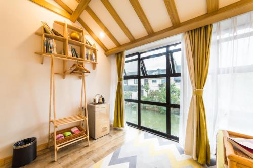 a living room with a large window and yellow curtains at Tongli Slowlife River View Inn in Suzhou