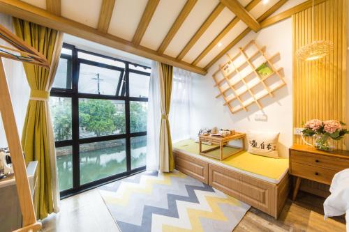 a bedroom with a large window and a bed with a desk at Tongli Slowlife River View Inn in Suzhou