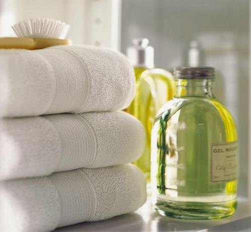 a stack of white towels next to a bottle of soap at Hotel du Commerce in Pontacq