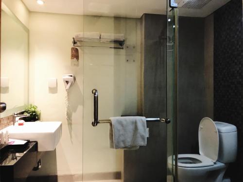 a bathroom with a toilet and a sink and a shower at Mercure Surabaya Grand Mirama in Surabaya