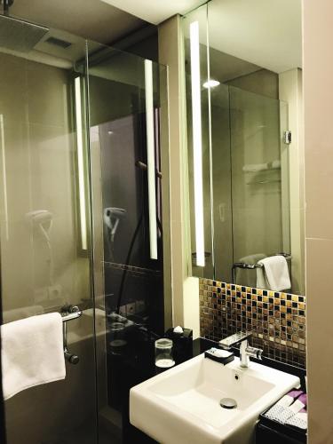 a bathroom with a sink and a shower with a mirror at Mercure Surabaya Grand Mirama in Surabaya