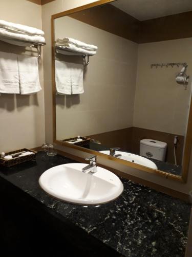 a bathroom with a sink and a mirror and a tub at Song Huong Hue Hotel in Hue