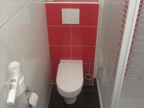 ein Badezimmer mit einem weißen WC und einer roten Wand in der Unterkunft Ferienwohnung Apfelbaum in Schonungen