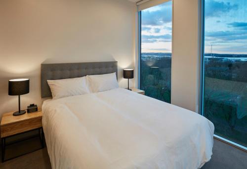 a bedroom with a large white bed and a large window at Swiss-Belsuites Victoria Park Auckland in Auckland