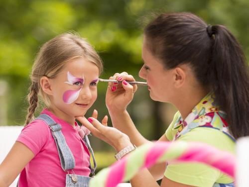a young girl getting her face painted by a woman at Gardaland Hotel in Castelnuovo del Garda