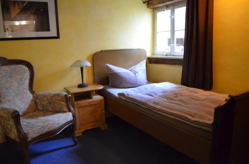 a bedroom with a bed and a chair and a window at Altstadt-Pension Koch in Goslar