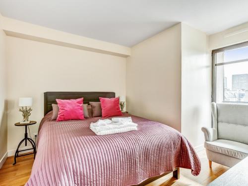 パリにあるWelkeys Apartment - La Fontaineのベッドルーム1室(ピンクの枕と椅子付きのベッド1台付)