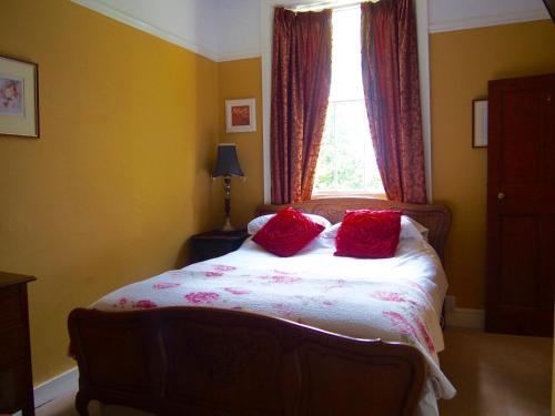 a bedroom with a bed with two red pillows on it at Wrangham House in Filey