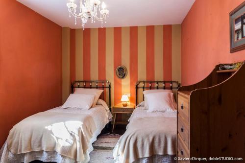 2 Betten in einem Zimmer mit orangefarbenen Wänden und einem Kronleuchter in der Unterkunft Casa Con Encanto in Badaguás