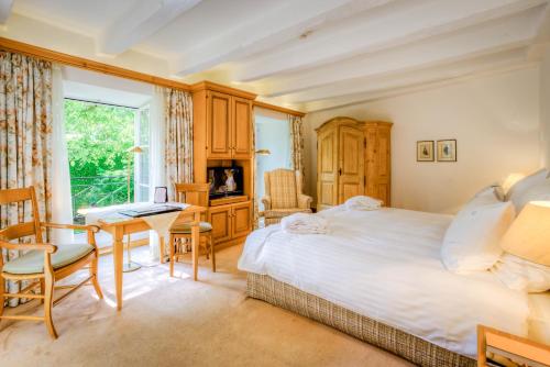 a bedroom with a bed and a desk and a window at A La Cour d'Alsace by HappyCulture in Obernai