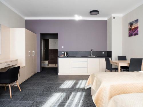 a bedroom with a bed and a table and a kitchen at Aparthotel CENTRUM Gliwicka 18 in Bytom