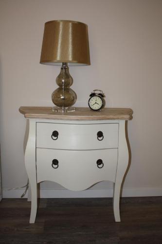 een lamp op een dressoir met een klok erop bij Areia Beach Guest House in Vila do Conde