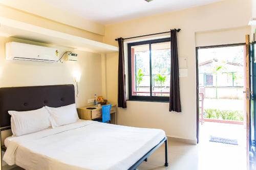 sypialnia z łóżkiem i oknem w obiekcie Lazy Frog Guest House w mieście Cavelossim