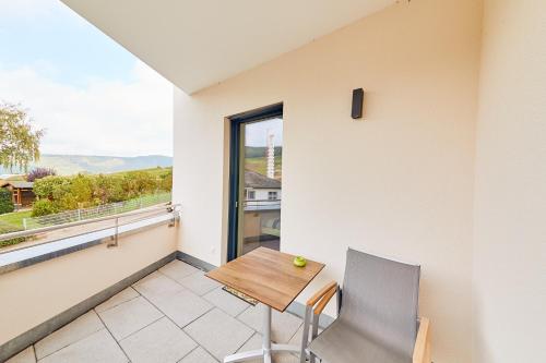 a balcony with a wooden table and chair and a window at Wein-Quartier Leo Pazen in Zeltingen-Rachtig