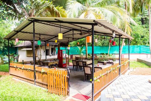 a restaurant with tables and chairs under a pavilion at Lazy Frog Guest House in Cavelossim