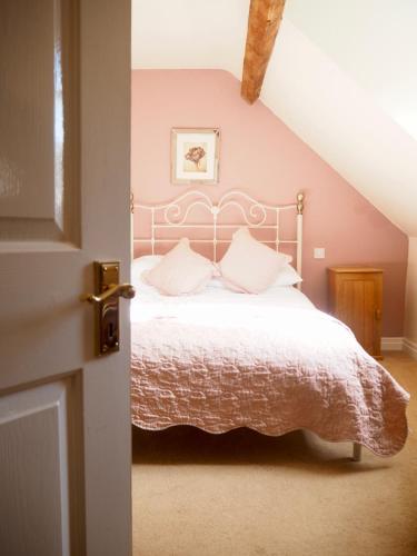a bedroom with a white bed with pink walls at Wrangham House in Filey