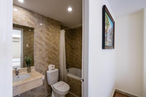 a bathroom with a toilet and a sink and a tub at Asian Ruby Center Point Hotel & Spa in Ho Chi Minh City