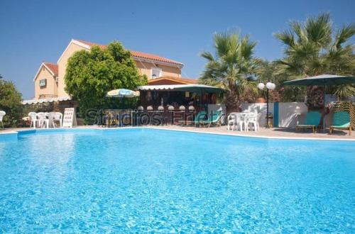 a large blue swimming pool with chairs and umbrellas at Erietta Studios in Svoronata