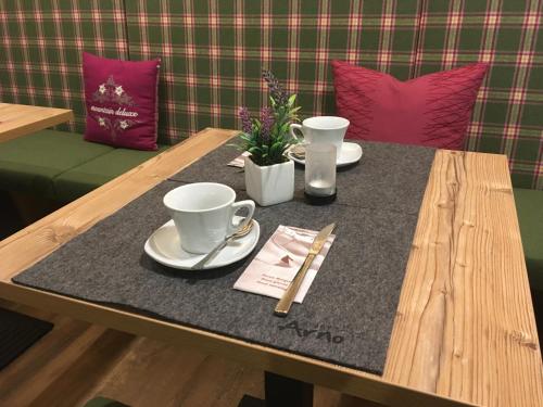 a wooden table with two cups and plates on it at Apart Hotel Arno in Sölden