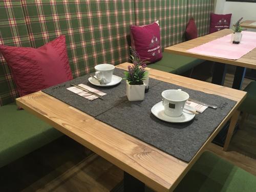 a wooden table with two cups and plates on it at Apart Hotel Arno in Sölden