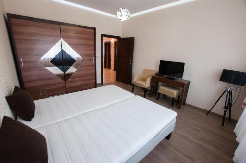ein Schlafzimmer mit einem weißen Bett und einem Schreibtisch in der Unterkunft Prestige apartment in Komárno