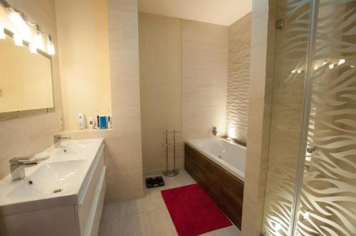Un baño con bañera, lavabo y ducha. en Prestige apartment, en Komárno